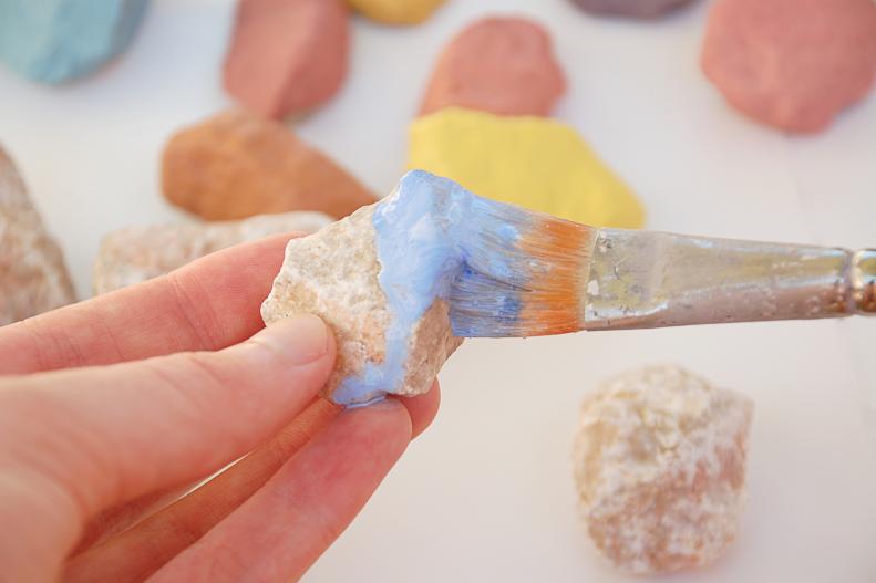 The first step towards creating your spelling stones is painting them a solid color. It’s easiest to paint the top half of the stone, let it dry and then flip it over to paint the bottom. Acrylic paint is permanent so make sure your workspace is covered. If the kids are getting involved make sure they wear something that can get a little paint on it!