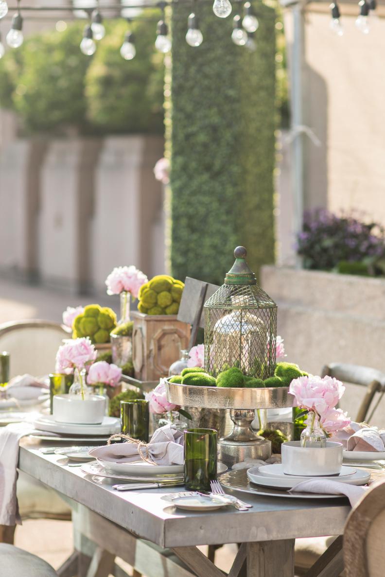 Hurley used metallic cake stands, wooden boxes with moss topiaries and vintage glass bottles of varying heights to create visual interest with the centerpiece.&nbsp;
