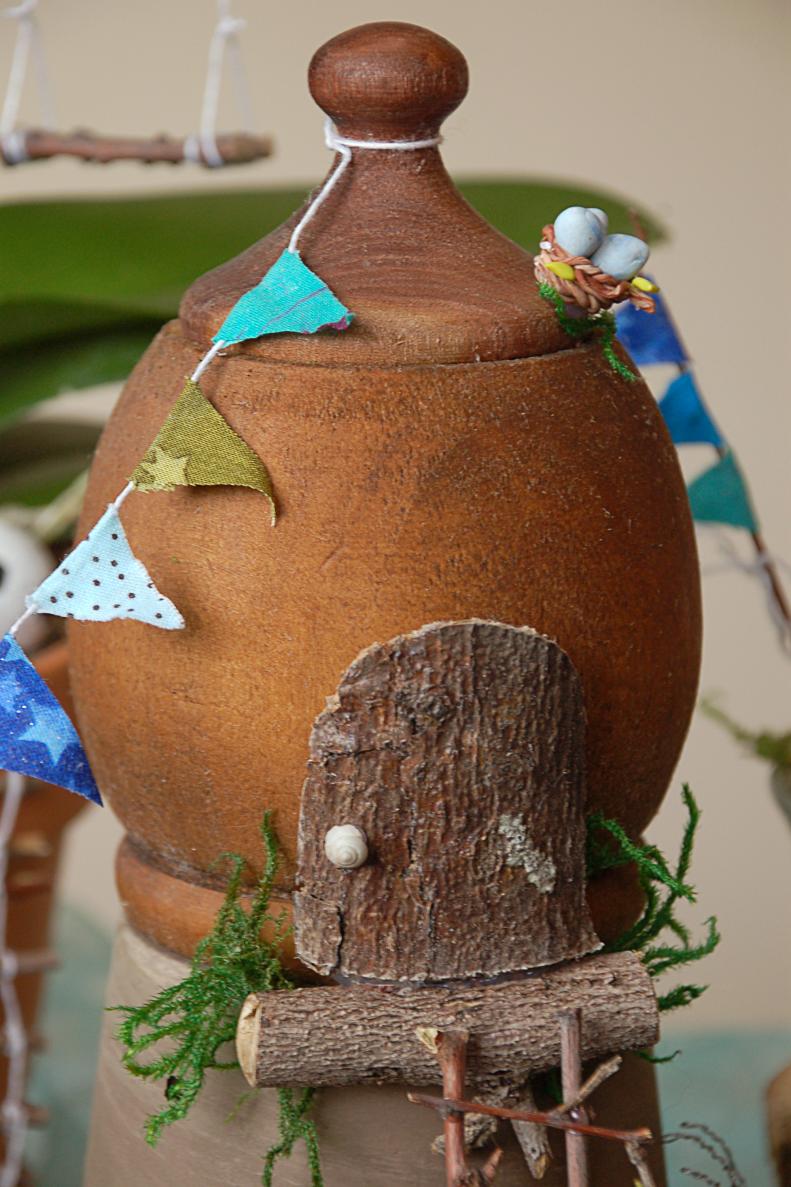 Create a little fairy cabin to go in your garden with a bit of bark and an interesting container. This wooden pot had a perfect roof shaped lid, and we added a door by carefully trimming a piece of bark to the right shape. Use hot glue to attach the door, and to add a handle. We used an empty snail shell from the garden!