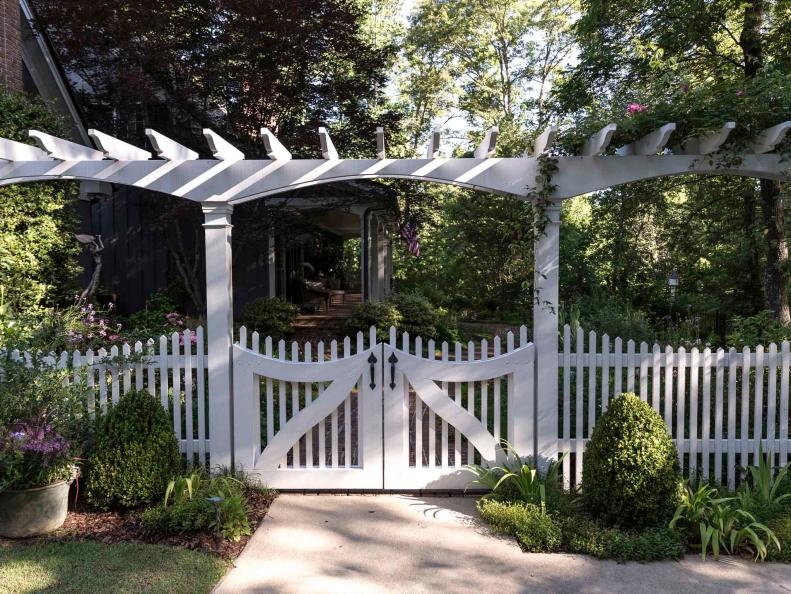 A white rose-topped pergola greets visitors and ushers them into the welcome garden beyond.