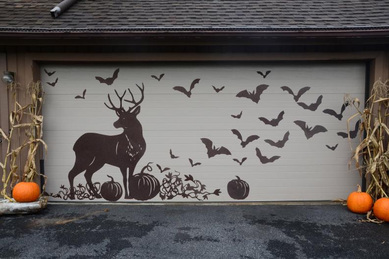 Decorate your garage doors this Halloween with vinyl decals. All you need are some sheets of adhesive vinyl, scissors and a little bit of time! We cut out a majestic buck looking out over a pumpkin patch while a colony of bats soars into the sky behind him. If your garage door rolls up and down, be sure to cut the vinyl at each seam in the door so the panels can move freely as the door opens.
