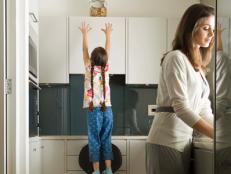 Girl reaching for cookie jar in kitchen with mother