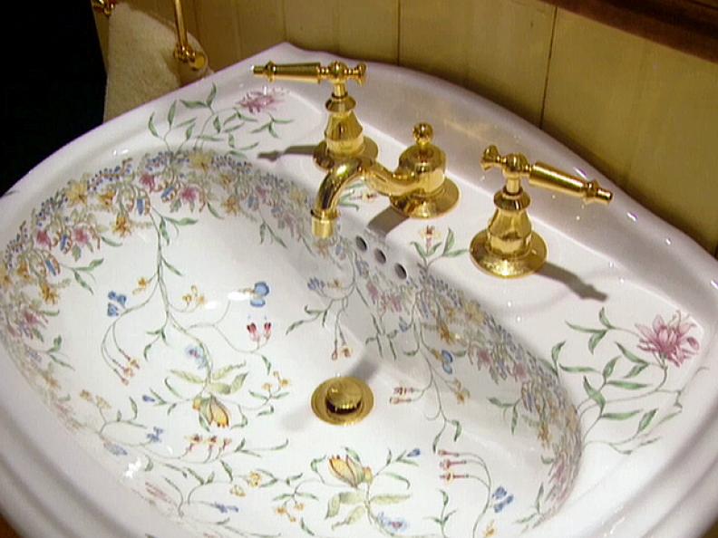 Brass sink faucet and handles with floral sink design in this white sink. This is one of the latest designs and styles of bathroom faucets.