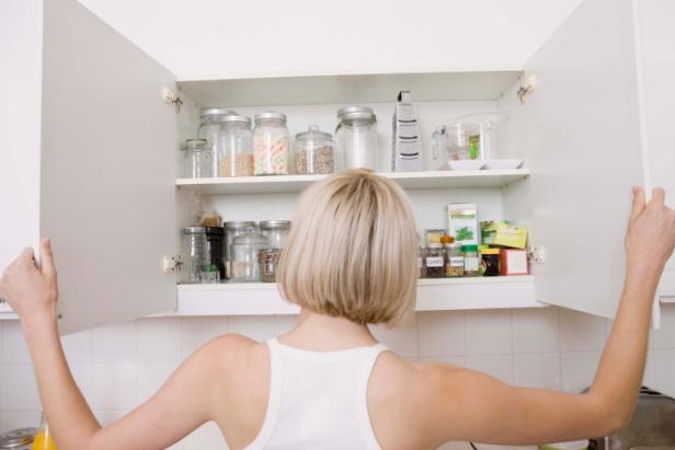 Woman opening kitchen cupboard