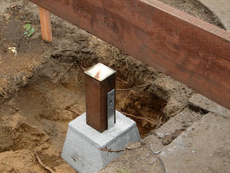 Close up of pier blocks set under the barn decking. With a sweet design and hard work, this backyard comes to life as a one hundred year old barn deck is set into place, a concrete chic fire feature and vibrant plants are incorporated into the mix.          