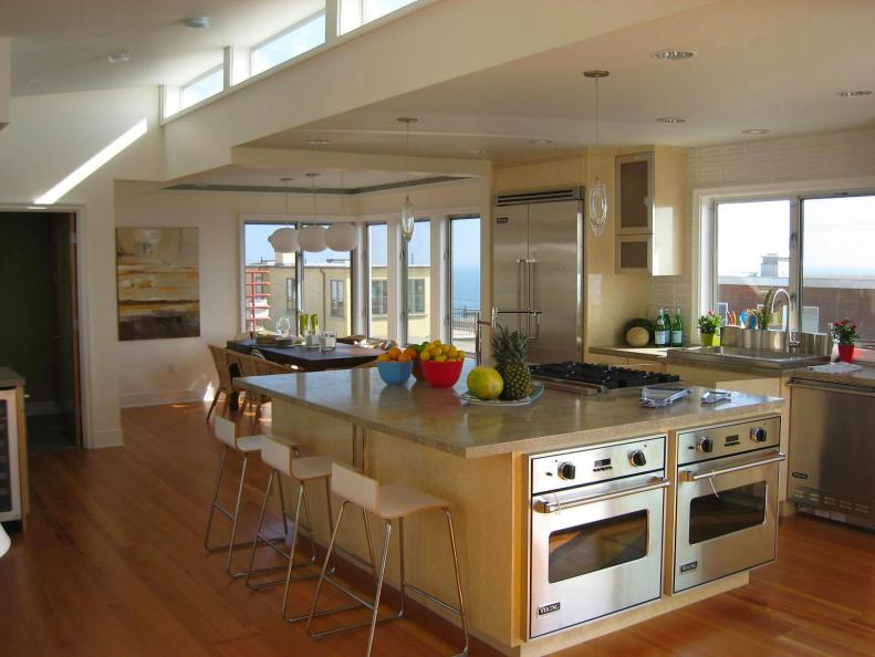 a contemporary beach house kitchen offers ocean views and breezes in a stylish setting.hardwood floors match the custom wood cabinets with granite countertops.stainless appliances including double ovens are tops.island bar gives extra seating plus more. 