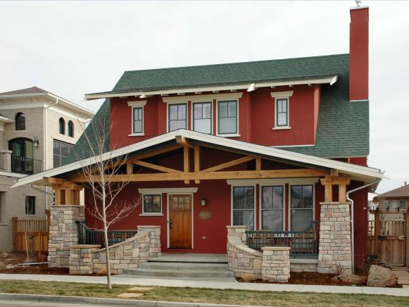 Red Craftsman Style Home With Stone Columns and Wood Trusses