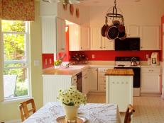 White kitchen cabinets with bright red walls.