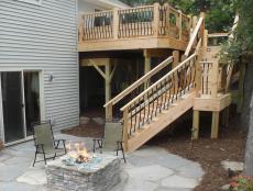 As seen on Sweat Equity, wood stairs are built to lead from the second level of this house down to the fire pit area with arched black raiing. 