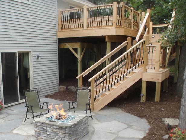 As seen on Sweat Equity, wood stairs are built to lead from the second level of this house down to the fire pit area with arched black raiing. 