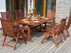 This outdoor dining space has teak patio furniture on a wood deck. 