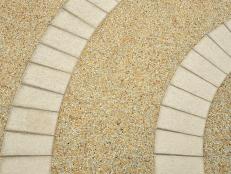 Pebble patio floor design with curved pavers in this backyard space. 