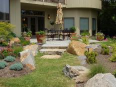 A beautiful landscaped patio idea with large boulders as part of the design and colorful flowers.