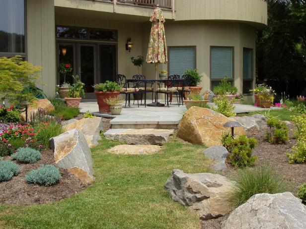 A beautiful landscaped patio idea with large boulders as part of the design and colorful flowers.