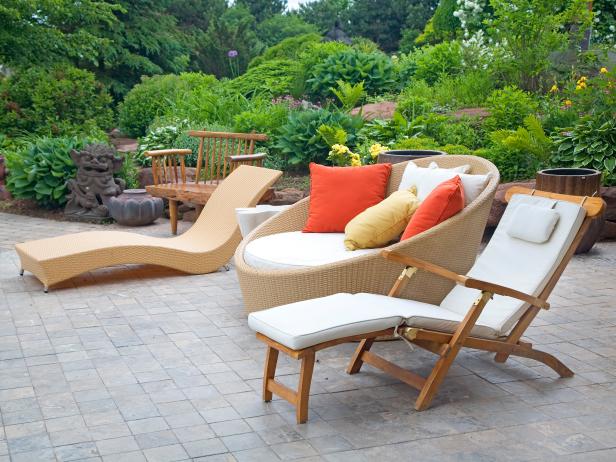 Three pieces of modern wicker outdoor garden furniture sitting on a concrete patio.