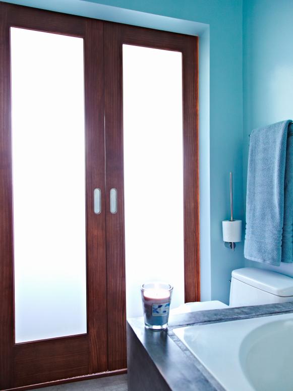 Bathroom's frosted glass doors permit room to flood with diffused light.