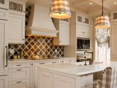 Traditional kitchen design with plaid seats and lighting, white cabinetry, decorative backsplash, and kitchen island.