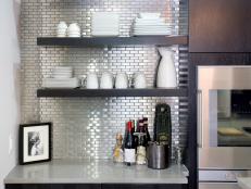 As seen on Kitchen Cousins, a tight shot of the stainless steel tile backsplash behind the open shelf cabinets in the kitchen.