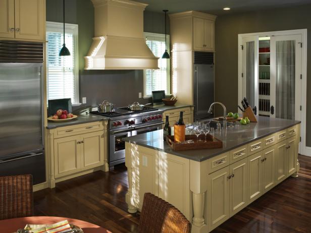 Wide view of a newly remodeled kitchen with dark countertops, large kitchen island, dark wood floor, and cream colored kitchen cabinets.
