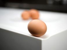 Closeup of a white Corian countertop design with an egg sitting on the curved edge of the counter. 