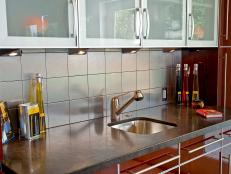 Asian modern kitchen sink and cabinet design with new faucets, tiled backsplash, and medium wood toned cabinetry. 