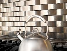 Metal backsplash behind the range and tea pot. This hip geometric design is a perfect complement for a contemporary kitchen. The tiles are made of white bronze and finished with a light patina. Photo Credit: Rocky Mountain Hardware