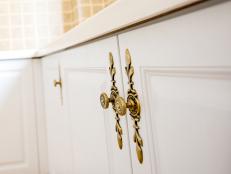 A detail shot of detail oriented knobs and accessories on white kitchen cabinet doors.