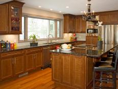 Cherry kitchen cabinets combined with Brazilian cherry wood flooring, a black granite countertop and a black glass chandelier complete this transitional kitchen.