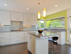 White sleek and modern kitchen cabinets with elegant lighting and kitchen island.