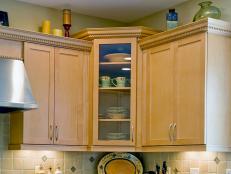 A tight shot of light colored wood corner kitchen cabinets with dishes stored inside.
