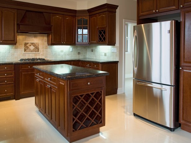 A wide angle shot of dark colored craftsman style kitchen cabinets.
