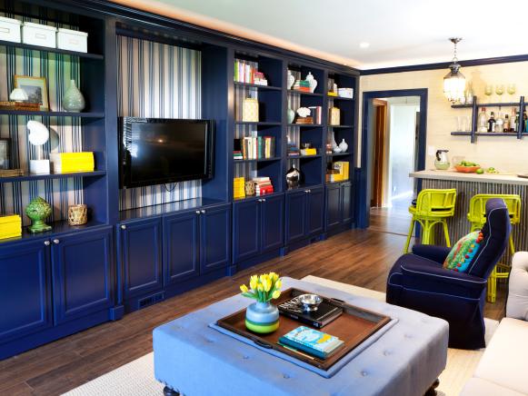 The living room in Kent and Jenny Longardner's home in Elmhurst, Illinois, after Design Star winner and Host Meg Caswell 's redesign, as seen on HGTV's Great Rooms, season 2 .The built-in library opens to unveil the door to the office, the tikky bar is in a corner and the facing wall is covered with a display of framed photos.
