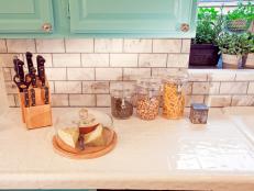 As seen on Desin on a Dime, Yu and Bunys kitchen, detail of the new carrera tiles backsplash. Casey gave a new life to the outdated kitchen with a fresh Heirloom Glam design style. New carrera tiles backsplash, chandelier, seating area and more counter space make a dramatic new space. 