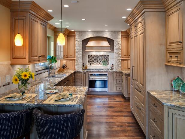 The two seats at the end of the kitchen countertops provide a small sitting area to congregate when entertaining. The stone surrounding the range hood has the warm, comforting look of a fireplace, and spice pull-outs and corner drawers maximize storage space.