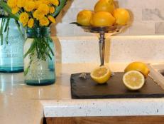 Closeup of a kitchen countertop made from laminate material and a marble tile backsplash. 