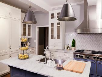 This kitchen features marble countertops and backplash, new appliances and range hood, a kitchen island with a farmer sink, after transformation by the crew of DIY Networks original series Kitchen Crashers.