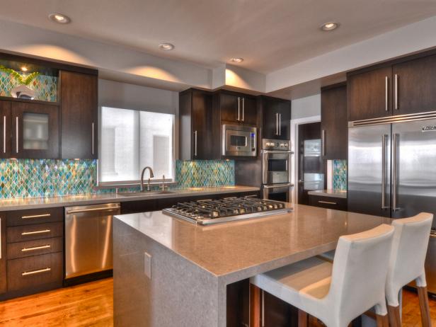 The backsplash takes the stage in the kitchen with the beauty of green and teal glass, placed against a dark espresso wood. The clean and contemporary design is brought throughout the entire space including the light gray quartz countertops. 