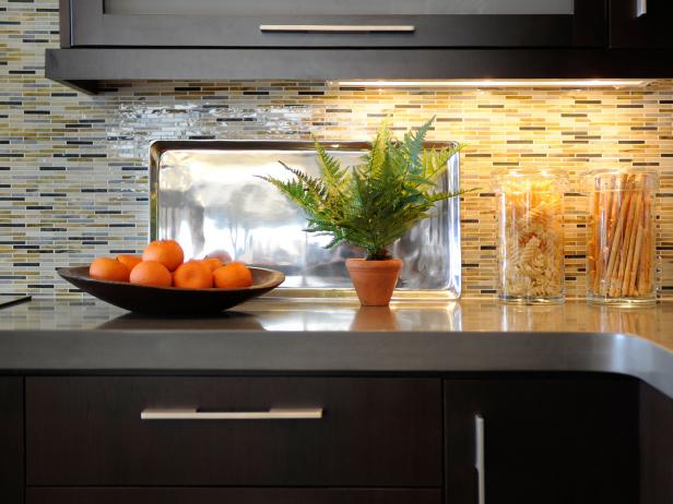 Closeup of a kitchen countertop with tiled backsplash and dark cabinetry. 