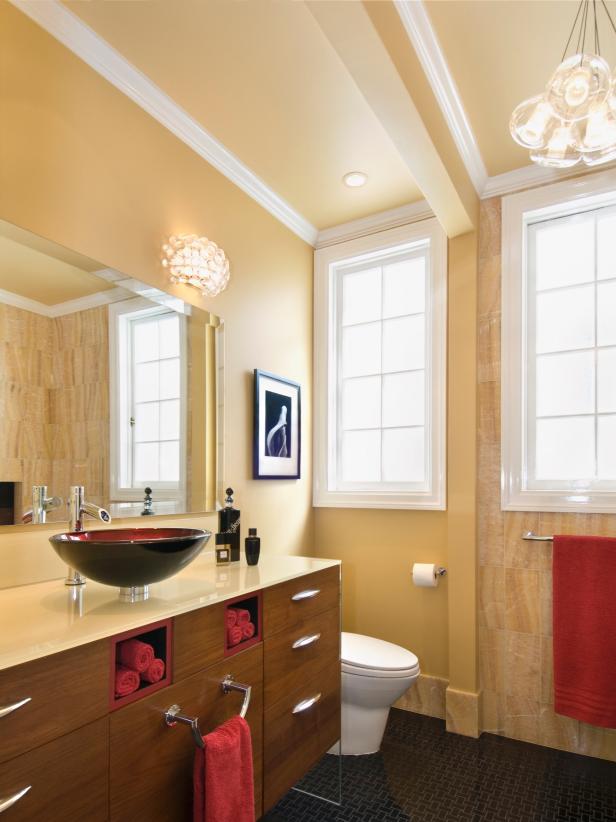 Neutral Colored Bathroom with a Red Sink and Towels.
