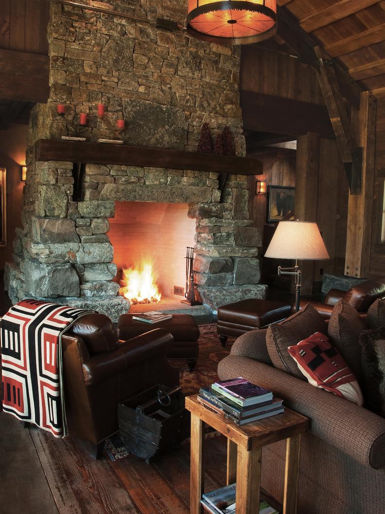 Barn beams supported by steel braces make the fireplace mantel. The fireplace is made of stone and has a rustic feel. 
