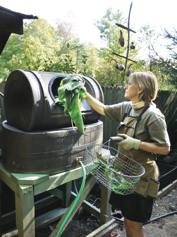 A woman is putting tea leaves into a barrell for composting.