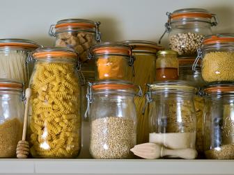 Off white walls in the pantry with old white traim on the shelf anchor the cream and white colors of the food staples. 