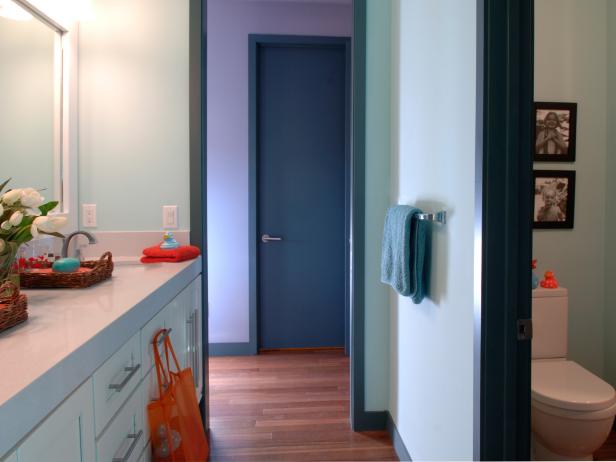A soft, robin's-egg blue was splashed on the walls to visually expand and brighten the space, while still incorporating deeper shades of blue for a sweet and interesting monochromatic look. To contrast with the blue surroundings, designer Linda Woodrum integrated pops of vibrant orange accessories in unexpected spots.