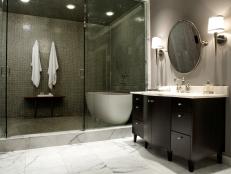 Two large shower doors open up into a tiled bathing area with a free standing white porcelain tub.