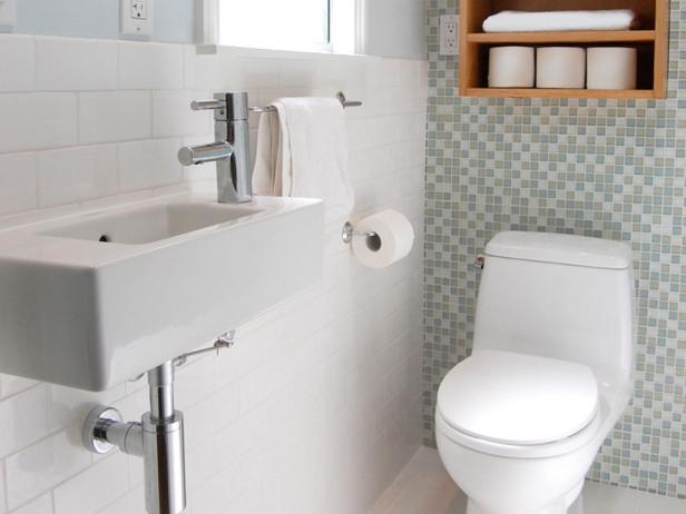 A cramped floor plan and outdated finishes prompted the remodel of this small master bathroom. Relocating the toilet to the rear wall and adding a wall-mounted sink maximizes the space. The glass mosaic tile feature wall adds movement and draws attention to the high ceilings and skylight.