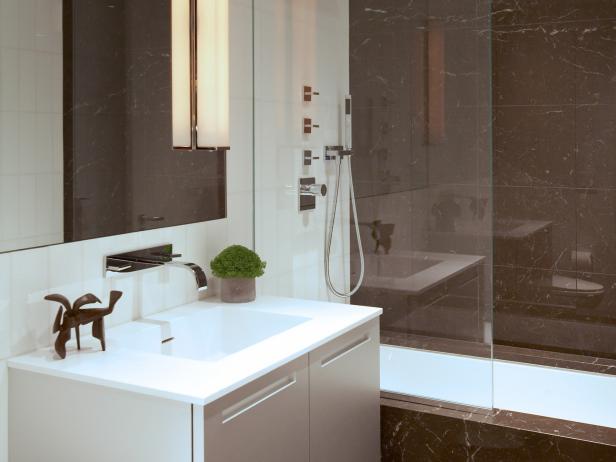 The guest bathroom has modern and clean lines and is a balance of light white glass tile and dark brown marble. Contrasts create drama and the bathroom feels warm yet crisp through its use of materials. Dimmers installed on the lighting allow you to create a softer light in the evening but still allow it to bright when shaving or applying makeup.