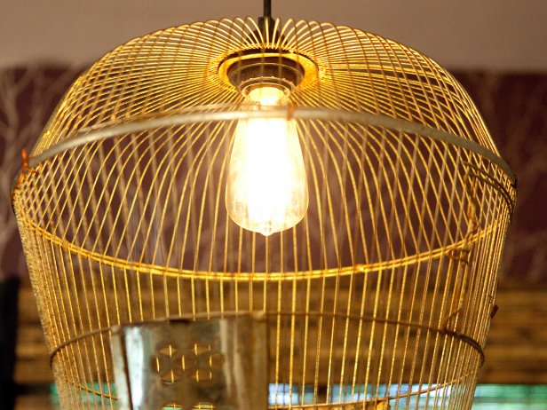 A playful light fixture made from a brass birdcage brings a romantic twist to the dining area.