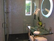 This guest bathroom created a big concern due to the small space Crisermy had to work with. Using a narrow glass and stainless steel vanity not only provides more space to enter the shower, but it also makes the space feel larger by not having a bulky furniture piece blocking the pathway.