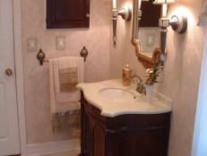 This ornate vanity combines with the mirror, wall sconces, and bath rug to give an Old World feel.