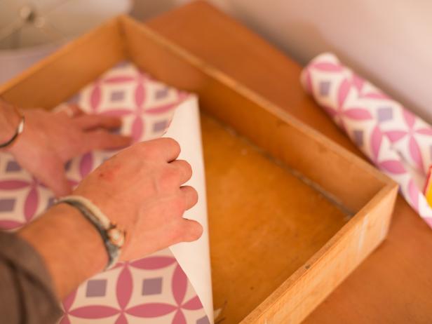 Step 3: Place Wallpaper
Place the wallpaper into the drawer completely dry (without paste) to ensure a perfect fit. Following manufacturerâ  s installation directions, permanently attach the paper to the drawer. This may require adding paste or simply wetting the back of the paper with water to activate a pre-pasted coating, then smoothing air bubbles out from the paper using wallpaper smoothing tool. Repeat for each drawer. TIP: If a valuable heirloom dresser is being used, consider simply laying the paper down inside the the drawer completely dry, holding it in place with double-sided tape rather than adhering with paste.